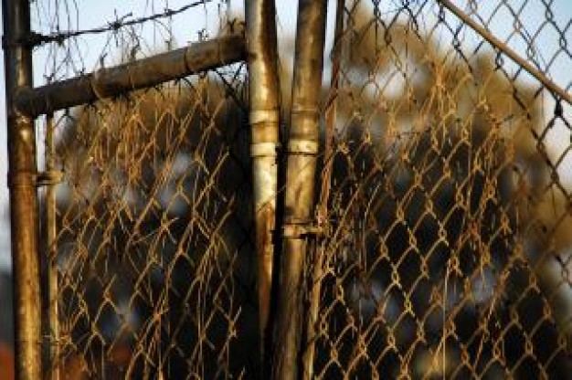 A badly rusted and warped chain-link gate
